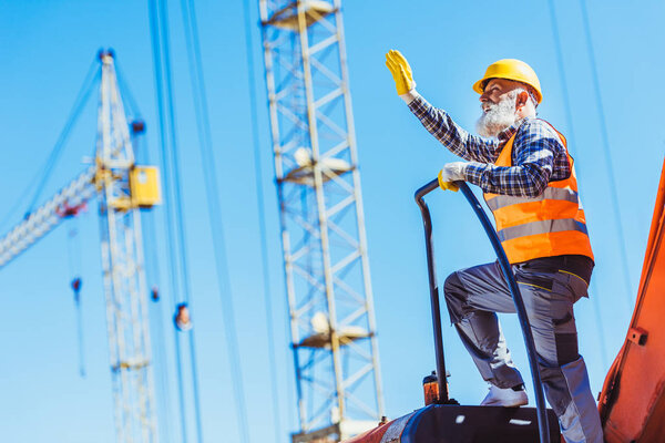 Construction worker on top of excavator cabin