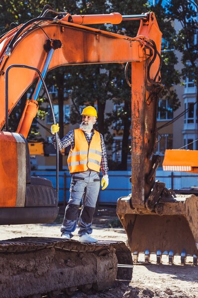 Construction worker posing with excavator