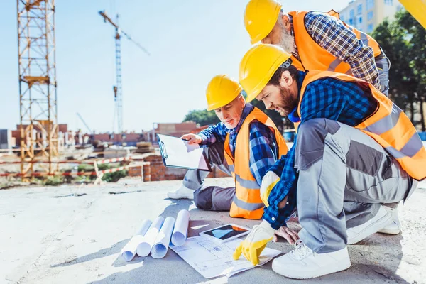 Bouwvakkers kijken bouwplannen — Stockfoto