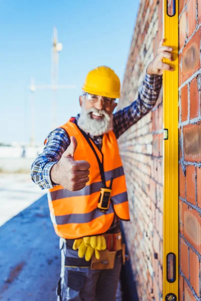 Trabajador con nivel de espíritu mostrando pulgar hacia arriba —  Fotos de Stock