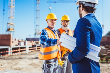 Construction worker and businessman shaking hands clipart