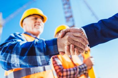 Builder and businessman shaking hands clipart