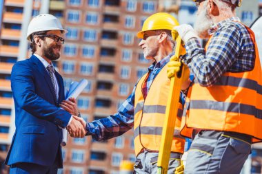 Construction worker and businessman shaking hands clipart