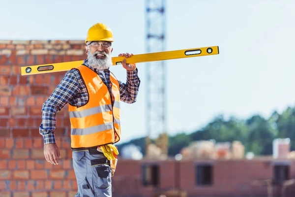 Trabalhador da construção sorrindo com nível de espírito — Fotografia de Stock