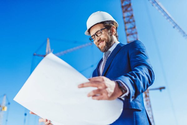 Businessman in hardhat examining building plans