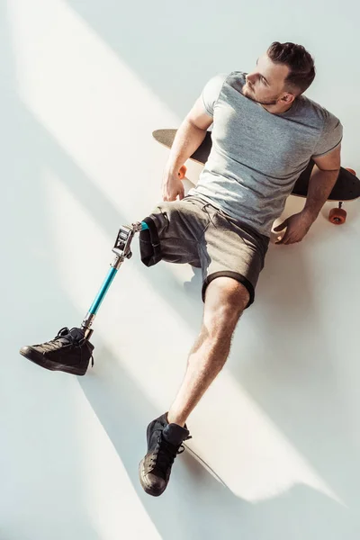 Человек с протезом ног отдыхает на скейтборде — стоковое фото