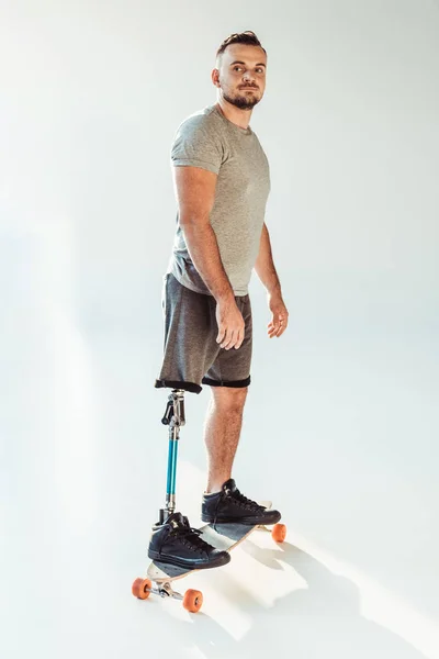 Человек с протезом ноги стоит на скейтборде — стоковое фото
