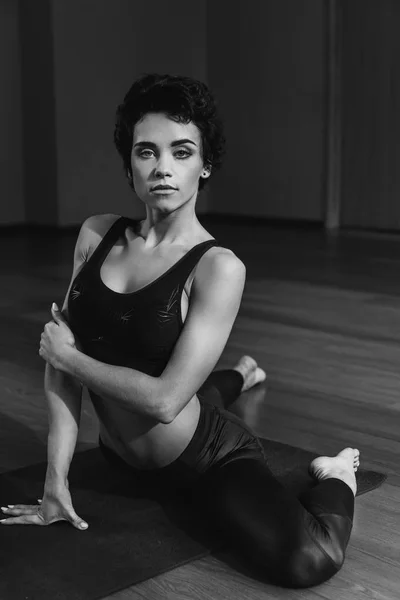 Женщина сидит на коврике для йоги — стоковое фото