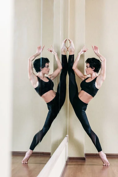 Woman doing stand split at mirror — Stock Photo, Image