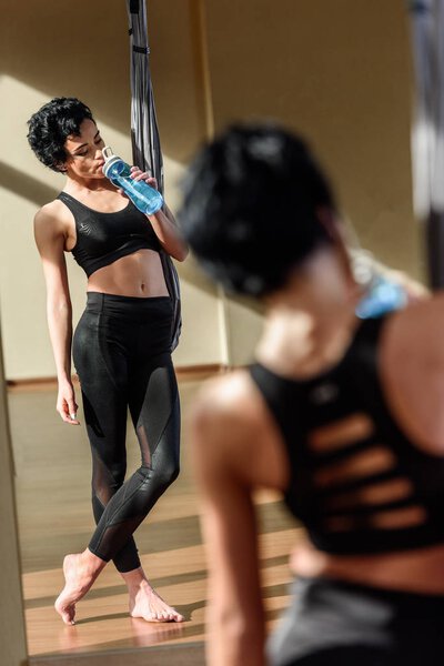 Женщина пьет воду после тренировки