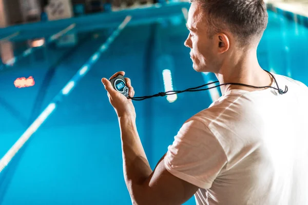 Trainer met stopwatch zwemmen bij zwembad — Stockfoto