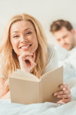 Yatağında kitap olan kadın.