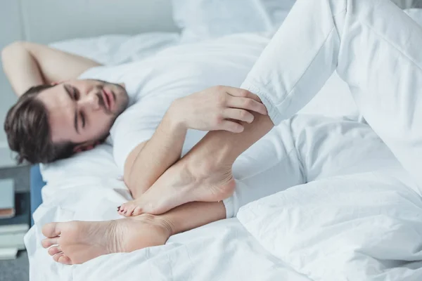 Muž dotýkání nohou přítelkyně v posteli — Stock fotografie