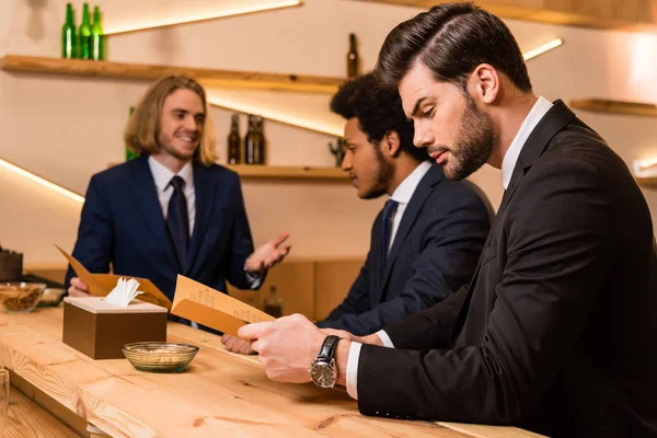 Businessmen with menu in bar — Stock Photo, Image