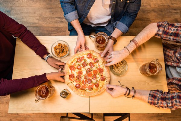 men drinking beer and eating pizza   