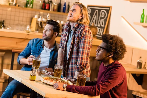 Vänner tittar på fotbollsmatch i bar — Stockfoto