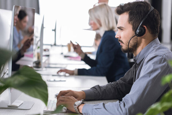 оператор колл-центра в гарнитуре в офисе
