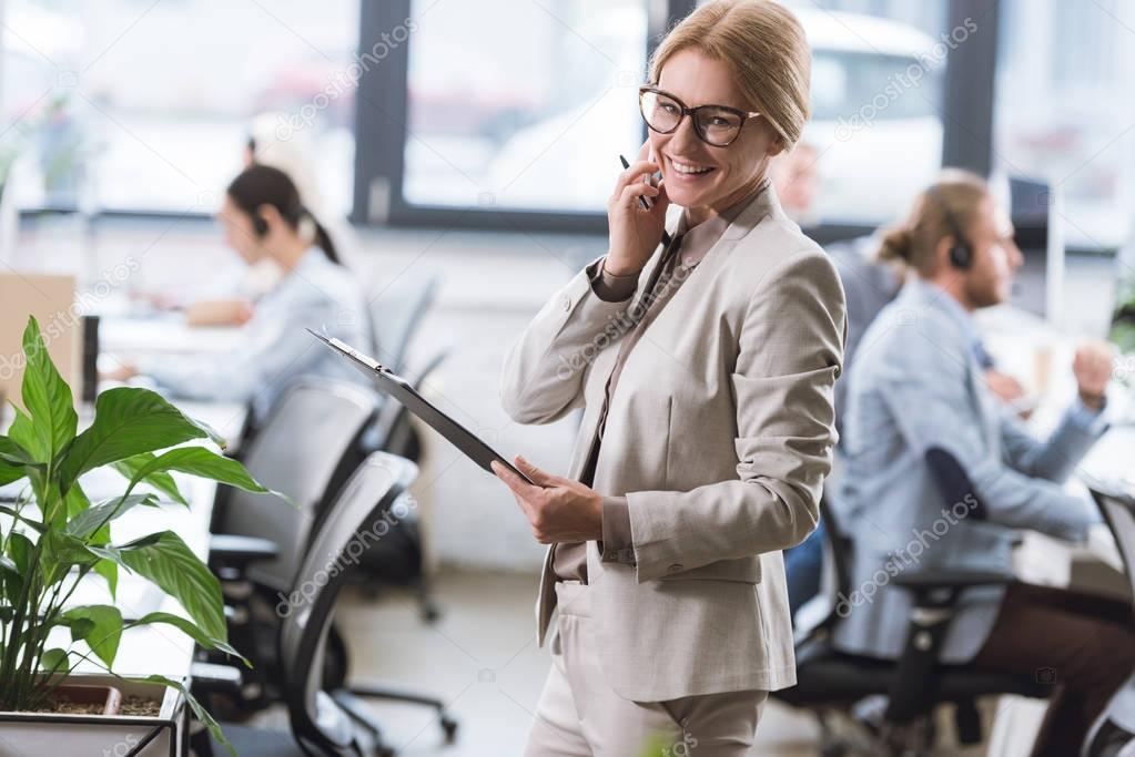 businesswoman with notepad talking on smartphone