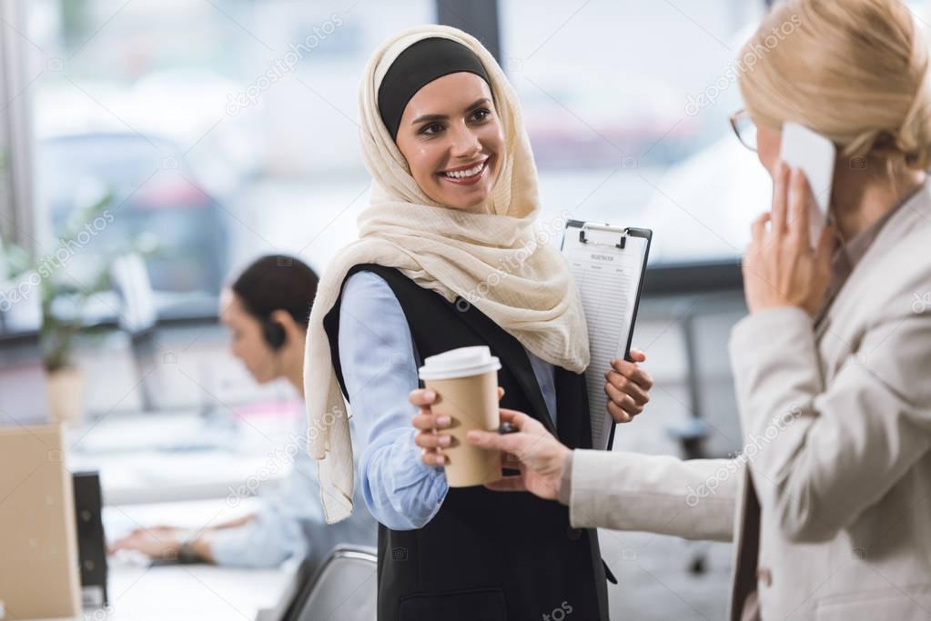 businesswoman giving coffee to colleague