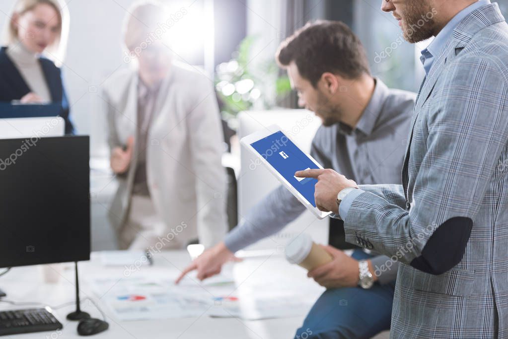 Selective focus of businessman using digital tablet with facebook logo on screen in office