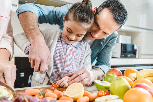 father with daughter slicing vegetables and fruits