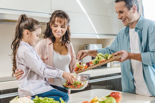 happy smiling family making salad together at kitchen 