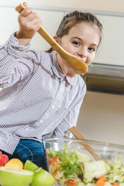 Barn med ladle spise salat - Stock-foto