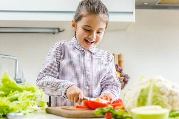 Kid slicing pepper on chopping board — Stock Photo, Image