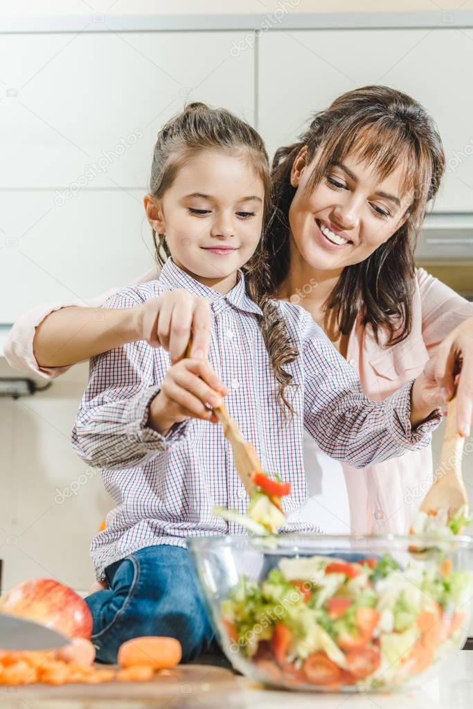 mother with daughter mixing salad