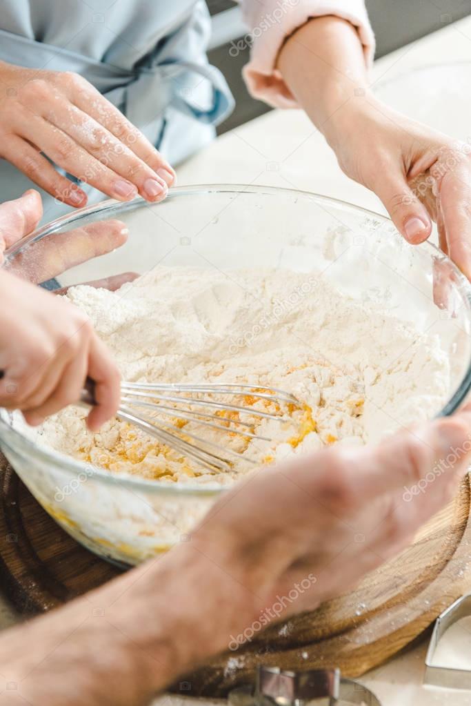 family hands mixing dough