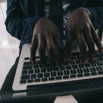 アフリカ系アメリカ人のビジネスマンがノート パソコンで作業のショットをトリミング