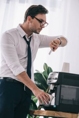 ofis makinesi kahve dökme ve bakarak işadamı