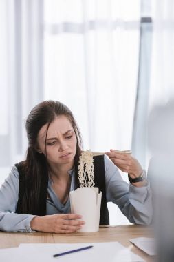 disgusted overworked manageress with box of junk take away noodles at workplace clipart