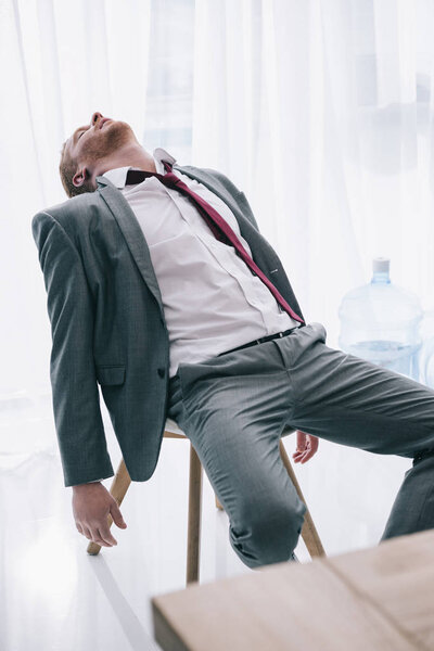 exhausted businessman sleeping on chair at office