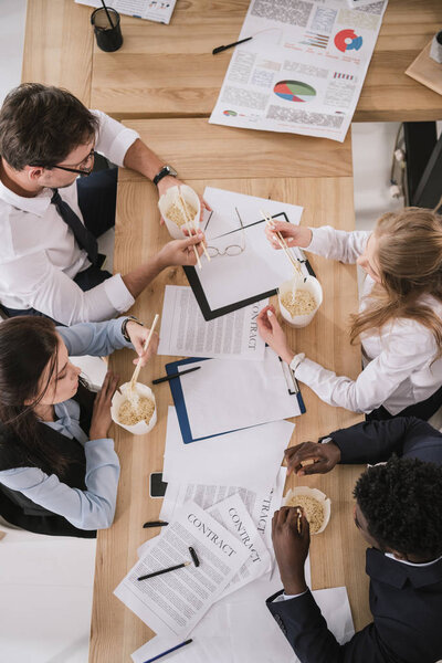 top view of sleepy zombie like businesspeople eating noodles at office