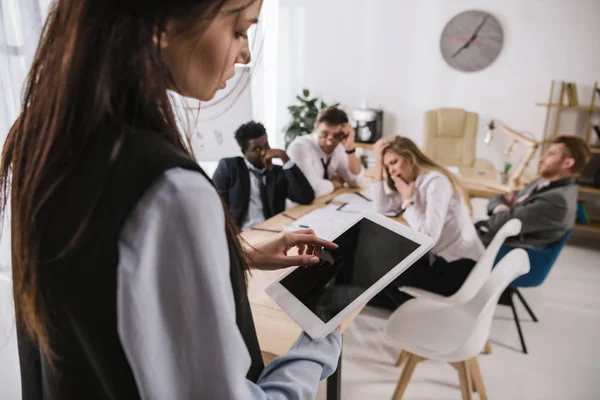 Empresária Usando Tablet Digital Com Colegas Embaçados Sentados Sala Conferências — Fotografia de Stock