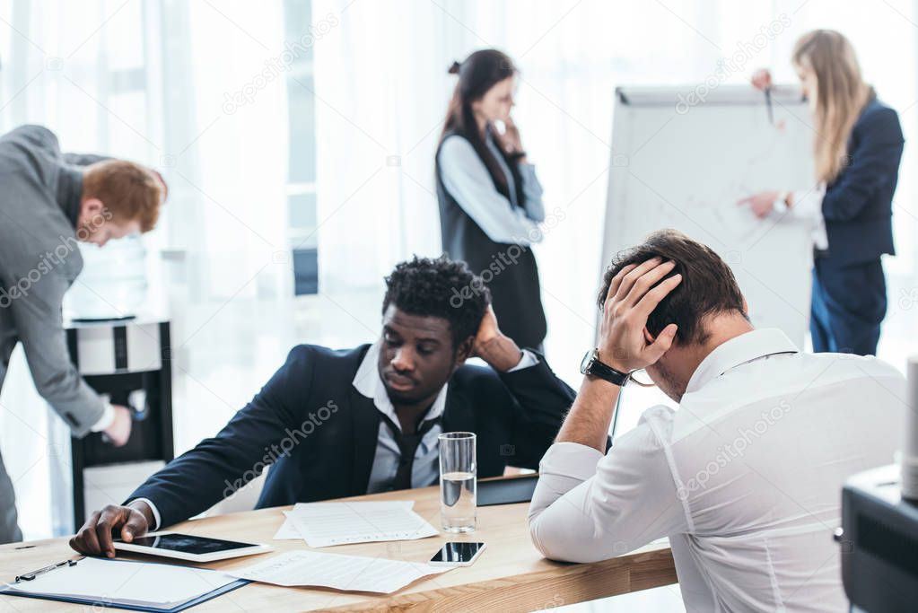 group of tired businesspeople in conference hall at office