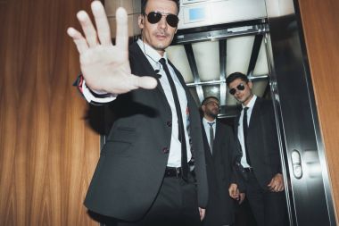 bodyguard obstructing paparazzi when celebrity going into elevator clipart