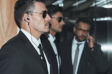 güneş gözlüğü ve smartphone tarafından konuşan işadamı korumalarından oluşan profil