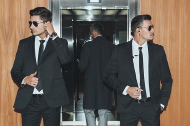 bodyguards reviewing territory when businessman standing in elevator  clipart