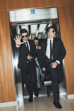bodyguard obstructing paparazzi when celebrity going out from elevator  clipart