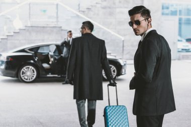 işadamı ile mavi tekerlekli çanta arabaya gidiyor 