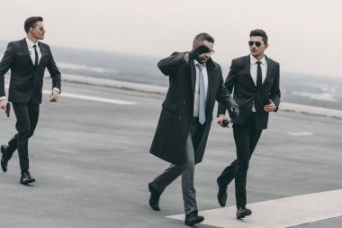 yüzünü eli ile kapsayan ve korumayla Helikopter pisti üzerinde yürüme işadamı