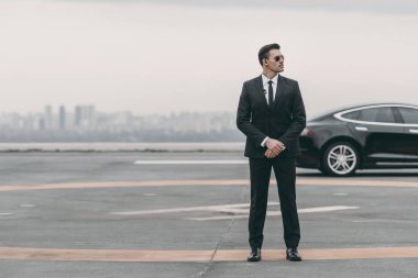 güneş gözlüğü ve helikopter pisti güvenlik kulaklığı ile ayakta ve uzağa bakarak ciddi koruma 