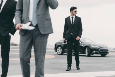 cropped image of bodyguards and businessman walking on helipad from car clipart