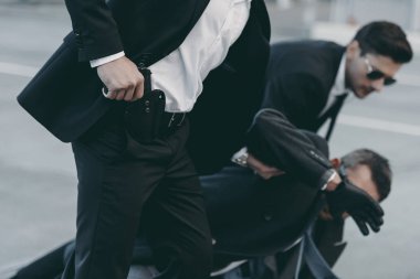 cropped image of bodyguards protecting falling businessman  clipart