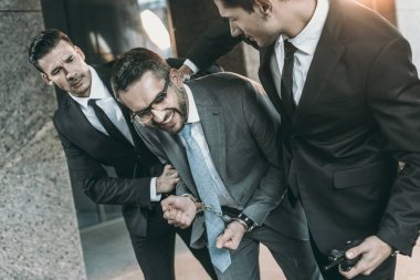 Güvenlik görevlileri gülümseyen suçlu tutuklamak kırpılmış görüntü 