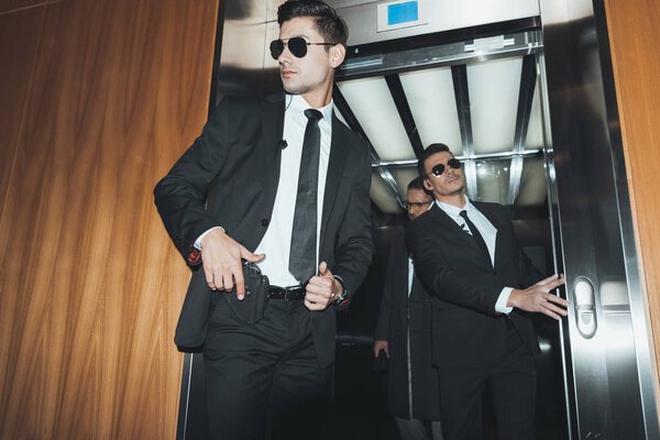 bodyguard putting hand on gun when going out with businessman from elevator 