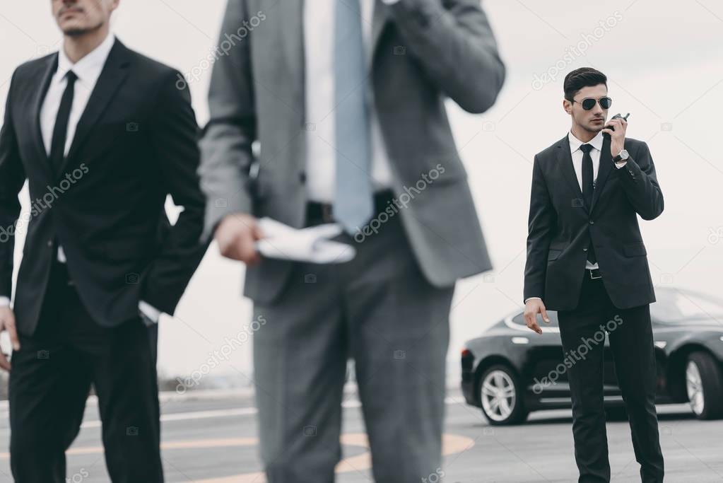cropped image of bodyguards and businessman walking on helipad 
