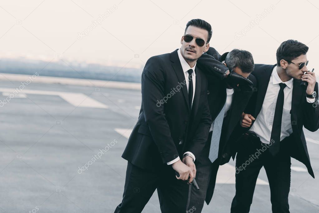 two bodyguards protecting businessman with gun 